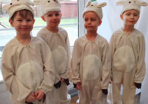 Czterech chłopców w roli Baranków stoi obok siebie podczas przedstawienia