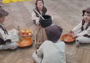 Czterech chłopców w roli Pastuszków siedzi przy ognisku.