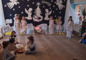 Na scenie prezentują się dzieci w rolach Maryi, Józefa, Gwiazdek, Aniołków, Pasterzy, Baranków, Królów. W tle dekoracja - na granatowym materiale przypięte są białe postacie aniołków, baranków, pastuszka, żłóbek, gwiazdki. Na górze świeci gwiazda betlejemska.