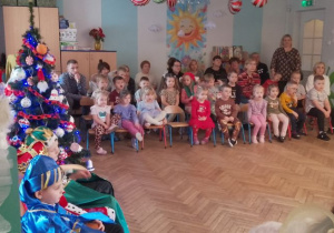 Dzieci i pracownicy przedszkola oglądają siedzą na krzesłach i oglądają przedstawienie jasełkowe.