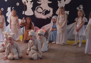 Chłopcy w roli Baranków uklęknęli na kolanach na środku sceny naśladując grę na dzwoneczkach. Gwiazdki i Aniołki śpiewają pastorałkę "Do be, do be, do Betlejem".