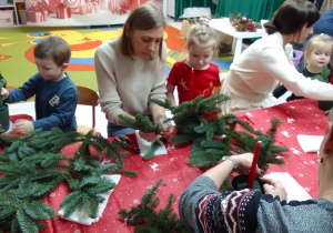 Michał, Maja z mamą i Marysia z mamą wykonują świąteczny stroik.