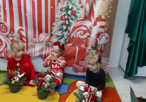 Emilia, Ala i Marysia siedzą na tle dekoracji, przed nimi – stroiki świąteczne.