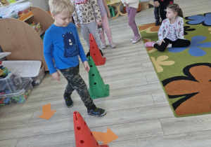 Karol idzie między pachołkami ułożonymi na podłodze zgodnie ze strzałkami leżącymi na podłodze.