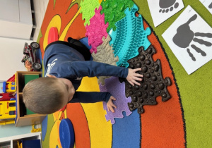 Michałek dotyka puzzle sensoryczne.