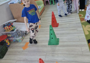 Olek idzie po torze przeszkód zgodnie ze strzałkami leżącymi na podłodze.