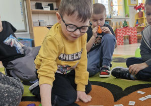 Antoś układa ciągi rytmów z kartoników ze śnieżynkami.