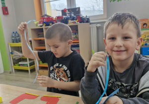 Stanisław i Franciszek siedzą przy stoliku w trakcie tworzenia pracy plastycznej.