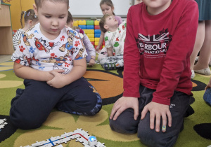 Szymek i Julek przyglądają się jeżdżącemu ozobotowi.