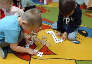 Szymon i Leon układają z "puzzli" drogę dla Ozobotów.