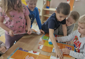 Przedszkolaki układają planszę z puzzli potrzebną do zabaw z robotami Doc.