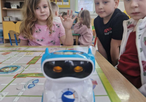 Przedszkolaki przyglądają się jeżdżącemu po planszy robotowi.