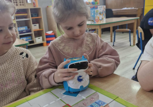 Oliwia ogląda robota do nauki programowania.