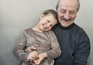Maja pozuje do zdjęcia siedząc na kolanach swojego dziadka.