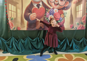 Alicja pozuje do zdjęcia na tle dekoracji w sali.