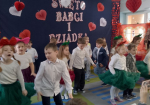 Dzieci tańczą Jive przy piosence. W tle dekoracja.