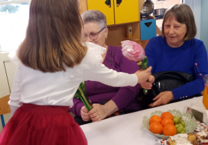 Marysia wręcza Babciom róże.