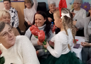 Tosia chodzi między stołami i wręcza Babciom róże.