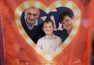 Antoś pozuje do zdjęcia z Babcią i Dziadkiem w fotobudce.
