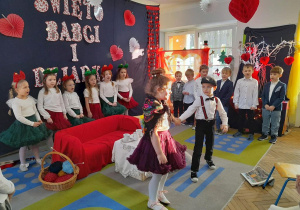 Nadia z Mikołajem tańczą na środku sceny. Z tyłu dzieci stoją obok siebie i śpiewają piosenkę.