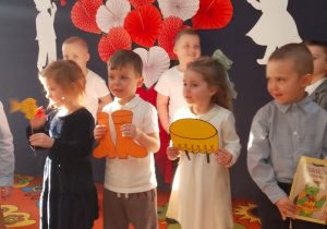 Grupka dzieci trzymająca rekwizyty w inscenizacji wiersza.