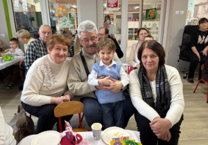 Michałek pozuje do zdjęcia ze swoimi babciami i dziadkiem.