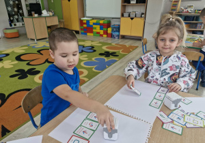 Szymon i Liliana programują Geniboty za pomocą specjalnych kart do kodowania.