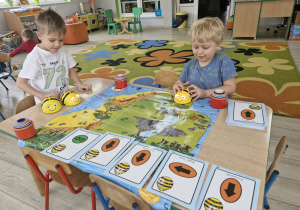 Ignacy i Karol za pomocą specjalnej maty i kart do kodowania programują pszczółki Beebot .