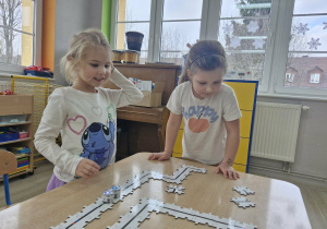 Ala i Maja z zaciekawieniem obserwują jadące po puzzlach Ozoboty.