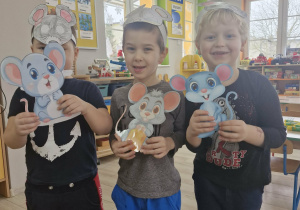 Szymek, Wojtuś i Karol trzymają w dłoniach obrazki z wizerunkami szarych myszek.