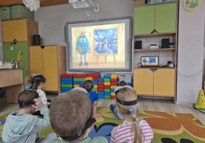 1. Dzieci siedzą na dywanie i oglądają film edukacyjny dotyczący życia pingwinów.