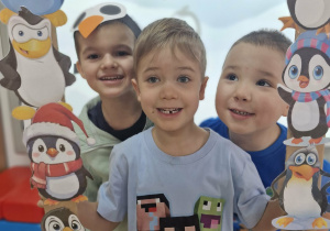 18. Staś, Ignaś i Szymek pozują do zdjęcia w foto-ramce z wizerunkami pingwinów.