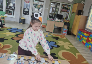 3. Oliwia stojąc przy stoliku układa obrazki z wizerunkami pingwinków w ciągu malejącym.