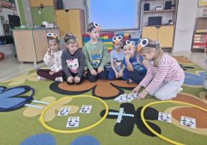 4. Dzieci siedzą na dywanie. Alicja przelicza obrazki z pingwinkami rozwiązując zadanie matematyczne.