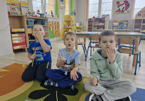 2. Chłopcy siedzą na dywanie i przesyłają całusy do zdjęcia.