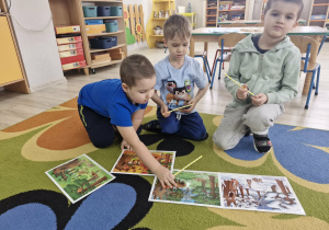 3. Dzieci siedzą na dywanie i układają obrazki w kolejności zdarzeń.