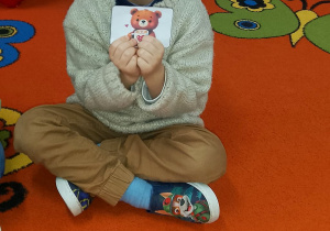 Filip rozwiązał zagadkę i trzyma przed sobą obrazek z misiem.