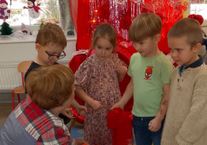 Dzieci wręczają upominek walentynkowy Pani Dorotce. W tle dekoracja walentynkowa na sali „Słoneczek”.