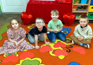 Dzieci siedzą na dywanie, a przed nimi leżą ułożone z części serca.