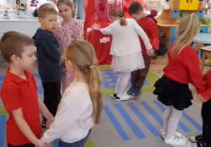 Dzieci w parach stoją na gazetowych sercach.