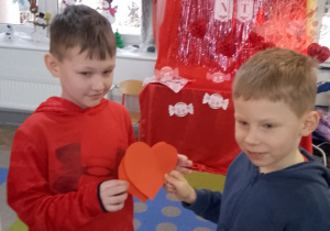 Antek i Bruno trzymają czerwone serduszka.