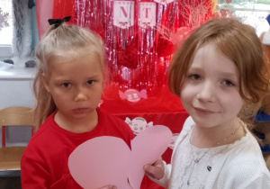 Tosia i Emma trzymają połówki różowego serca.