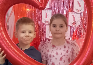 Marysia i Bruno pozują do zdjęcia w ramce balonowej w kształcie serca.