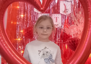 Zuzia pozuje do zdjęcia w ramce balonowej w kształcie serca.