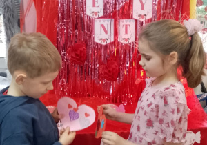 Marysia i Bruno wymieniają się kartkami walentynkowymi na tle dekoracji.