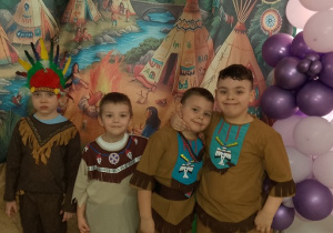 Chłopcy pozują do zdjęcia. W tle wioska indiańska.