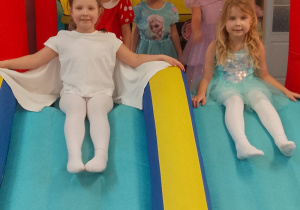 Dziewczynki zjeżdżają z nadmuchanej zjeżdżalni.