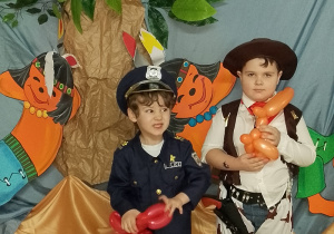 Michał i Julian pozują do zdjęcia, trzymając w rękach balonikowe pieski..