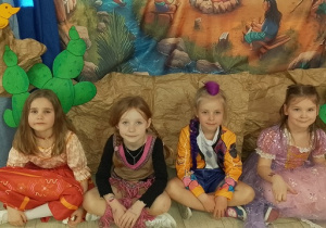 Dziewczynki siedzą i uśmiechają się do zdjęcia.