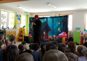 Krasnoludek Niezabudek pokazuje dzieciom kolorową skarpetę.